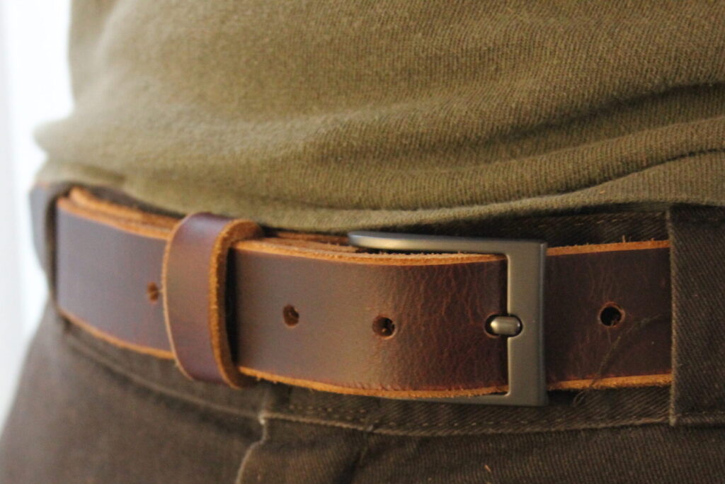 Dark brown full-grain leather dress belt worn with olive trousers